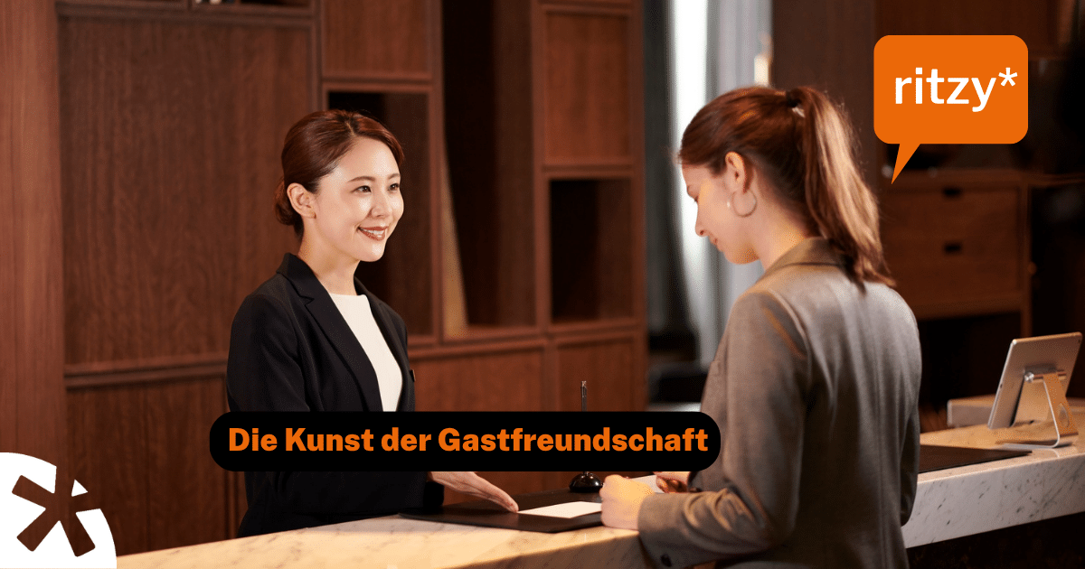 Zwei lächelnde Mitarbeiterinnen an der Hotelrezeption begrüssen einen Gast herzlich – Symbolbild für gelebte Gastfreundschaft.